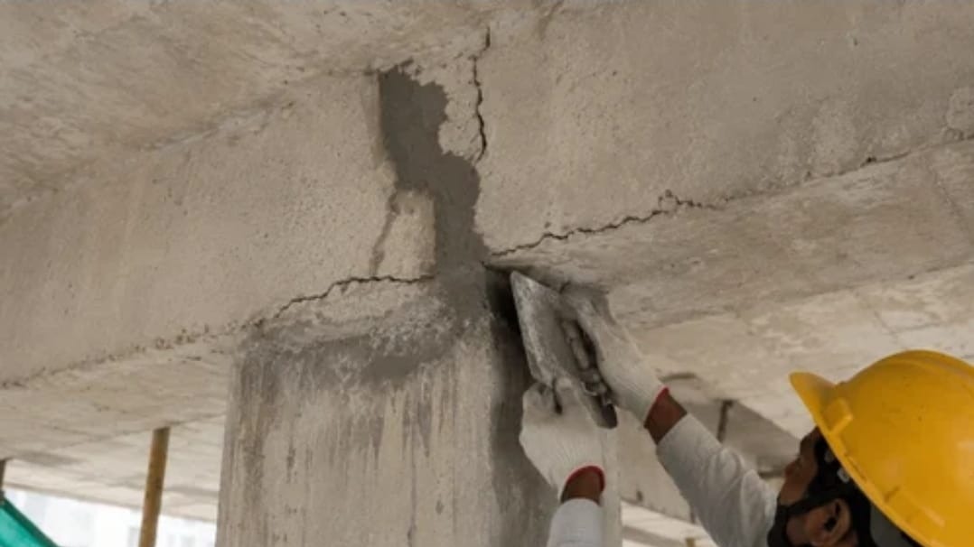 Applicator filling and finishing a crack at a concrete beam and column junction